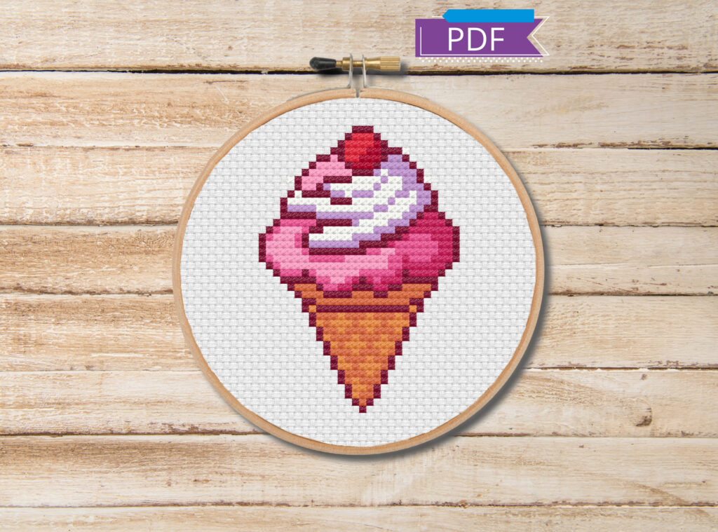 Ice cream cone cross stitch in an embroidery hoop on a wooden table.